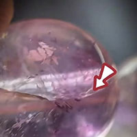 Photo of natural Amethyst bead with natural internal cloud and fracture marks, used in TrueZenGem identification guide to distinguish real Amethyst from uniform-colored glass, synthetic and dyed crystal imitations.